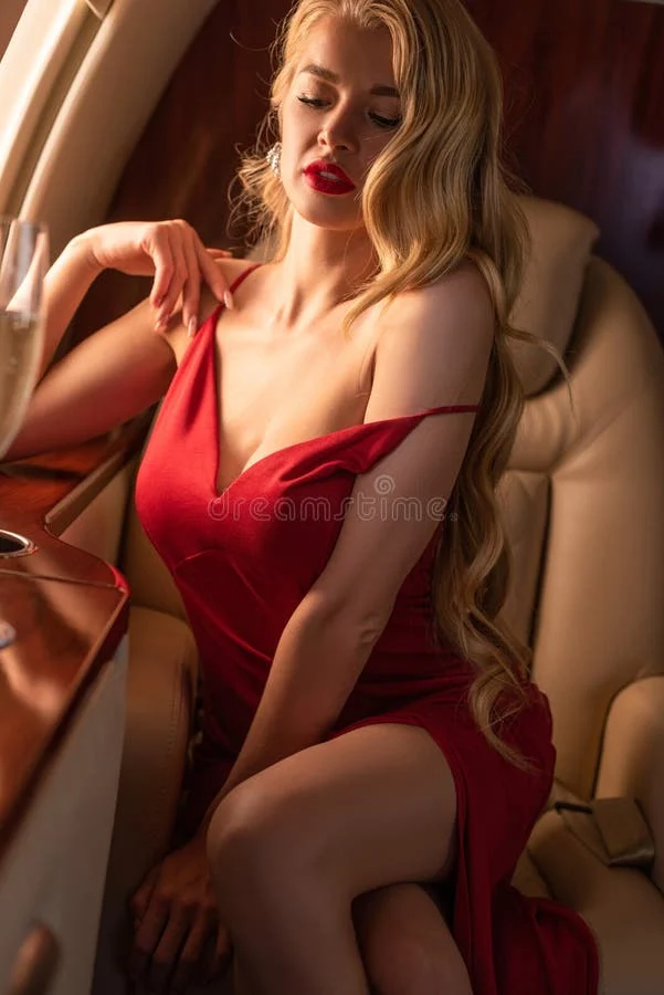Woman in a red dress seated in a luxurious interior, exuding elegance and confidence.